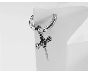 Detail of gothic silver cross earring with skull and black stone in punk style