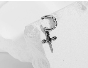 Macro detail of gothic cross earring with skull carving and black zircon on stone