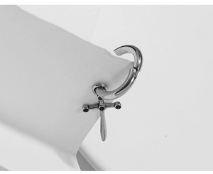 Detail of silver vintage gothic cross sword earring on a minimalist stone pedestal