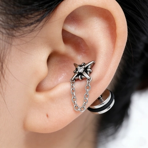Dark steel cross earring with star-shaped zircon and chain dangle on model ear