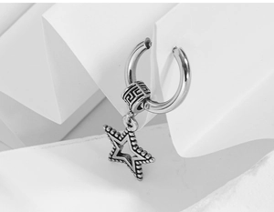 Macro detail of stainless steel earring with star pendant and engraved greek patterns