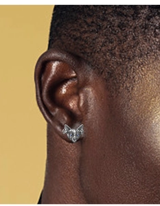 Detail of silver cat stud earring with blue gem eyes worn by a male model