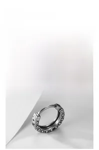 Detailed view of silver huggie earring with vintage textured dot pattern and aged finish