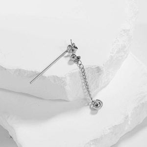 Minimalist silver cross drop earring in titanium steel on a white stone background