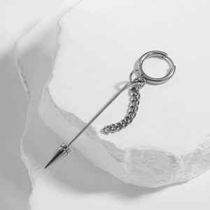 Silver punk hoop earring with polished long spike and fine chain on white stone surface