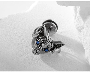 Macro shot of sphinx cat stud earring with blue zircon eyes and punk metal rings