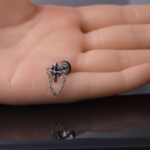 Macro shot of stainless steel cross earring with zircon stone and hanging chain detail