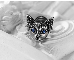Macro shot of vintage silver gothic sphinx cat earring with blue sapphire eyes and ear rings