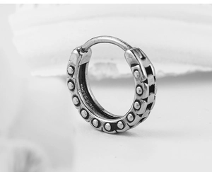 Detailed close-up of retro stainless steel hoop earring with embossed punk dots