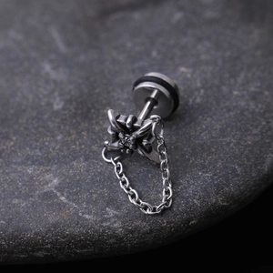 Macro shot of punk stainless steel cross stud earring with zircon and chain on dark stone