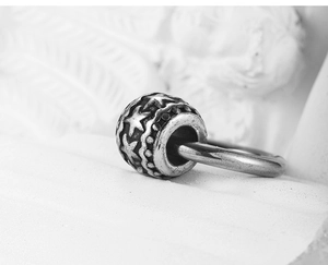 Vue macro d'une perle en argent vintage avec étoiles en relief et finition oxydée texturée