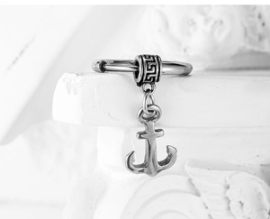 Macro detail of retro anchor pendant with geometric bead on minimalist metal earring