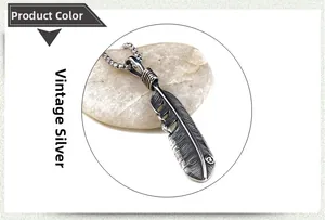 Detailed view of antique silver feather pendant with intricate textures on smooth pebble