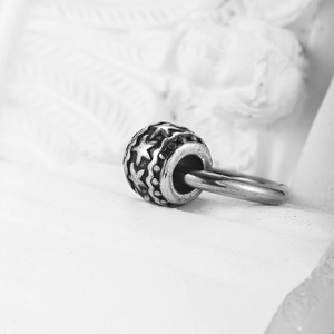Perle de charme étoile en argent vintage avec finition oxydée sur fond marbre