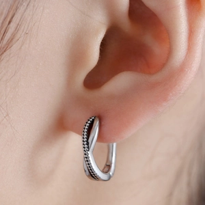 Minimalist silver twist hoop earrings with polished finish and beaded texture detail