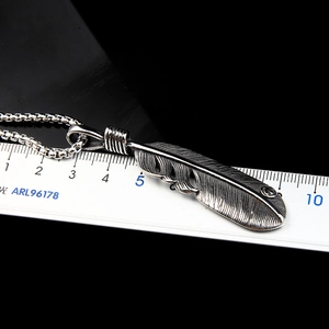 Detailed view of a vintage stainless steel feather pendant with ruler measuring 5.5cm length