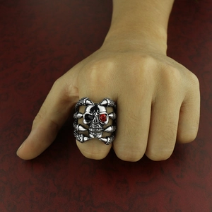 Punk style skull ring for men with red gemstone and skeletal claw band in silver finish