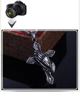Détail macro du pendentif croix en acier inoxydable vintage avec mains en prière