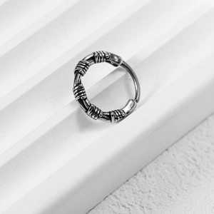 Retro stainless steel cross earring with spiral texture shown on white minimalist stand