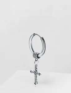 Macro detail of retro stainless steel cross earrings with intricate vintage engravings