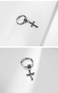 Detailed view of vintage surgical steel hoop earring featuring a cross pendant and pattern