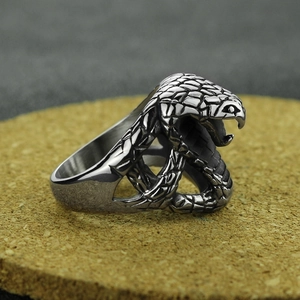 Vintage stainless steel cobra snake ring with detailed scales on a cork surface