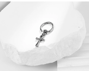 Detailed view of polished silver Ankh cross pendant earring on white stone surface