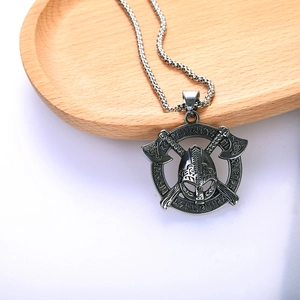Viking warrior helmet and double axes pendant on stainless steel chain over wooden tray