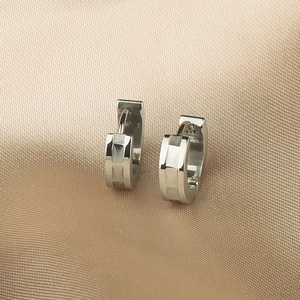 Détail de boucles d'oreilles créoles en acier argenté avec design géométrique facetté