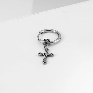 Retro stainless steel hoop earring with vintage cross pendant on a white geometric stand