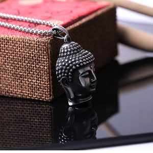 Pendentif tête de Bouddha vintage en acier inoxydable argenté sur surface réfléchissante