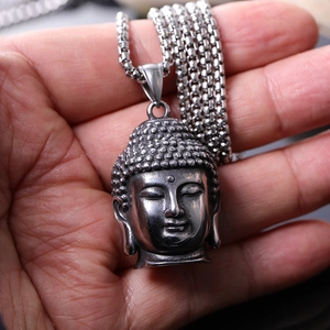 Détail macro d'un pendentif tête de Bouddha vintage en acier titane avec chaîne vénitienne