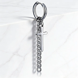 Macro detail of silver stainless steel earring featuring chunky chain and cross pendant