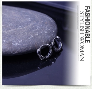 Detail of vintage silver hoop earrings with relief texture on a dark reflective surface
