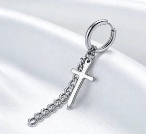 Macro shot of silver hip-hop earrings with cross pendant and chain on white silk