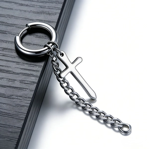 Macro detail of polished stainless steel huggie earring with cross pendant and chain