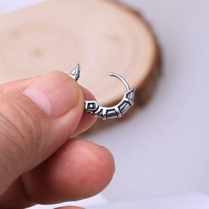 Macro shot of vintage stainless steel hoop earring with textured gothic engraving detail
