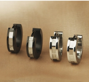 Vue détaillée de boucles d'oreilles huggies en acier brossé argenté et noir sur soie