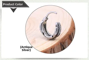 Detail of antique silver hoop earring for men with intricate feather texture on wood