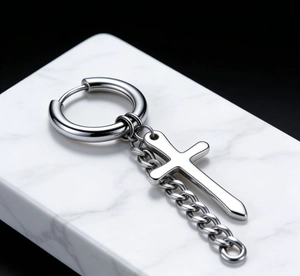 Macro shot of silver stainless steel cross earring with a cuban link chain detail