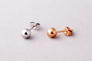 Close-up of polished silver and rose gold ball earrings with butterfly backings