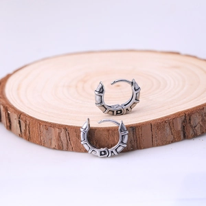 Men's stainless steel hoop earrings with industrial texture on natural wood background