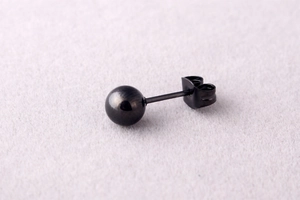 Detailed close-up of 4mm black ball stud earring with butterfly clasp on purple fabric