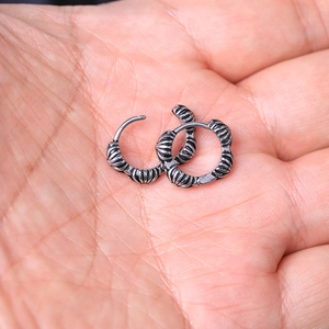 Detailed macro view of vintage textured stainless steel hoop earrings held in hand