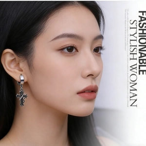 Close-up of vintage silver cross earring with gothic texture on a female model