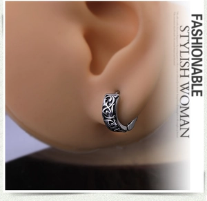 Macro detail of men's stainless steel hoop earring with vintage dragon totem engraving