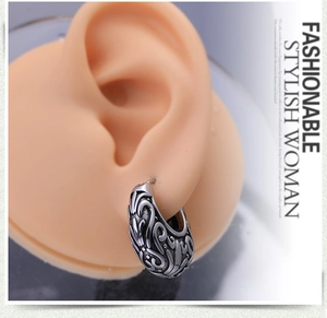 Macro detail of retro engraved stainless steel hoop earring on a model