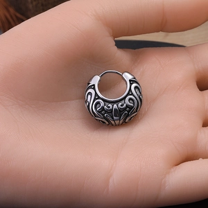 Macro shot of vintage engraved silver stainless steel hoop earring with detailed patterns
