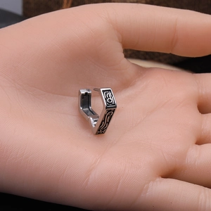 Gros plan de boucles d'oreilles triangle vintage en argent avec gravure noire sur main