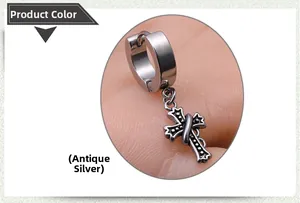 Close-up of vintage silver cross charm drop earring with weathered finish and hoop clasp